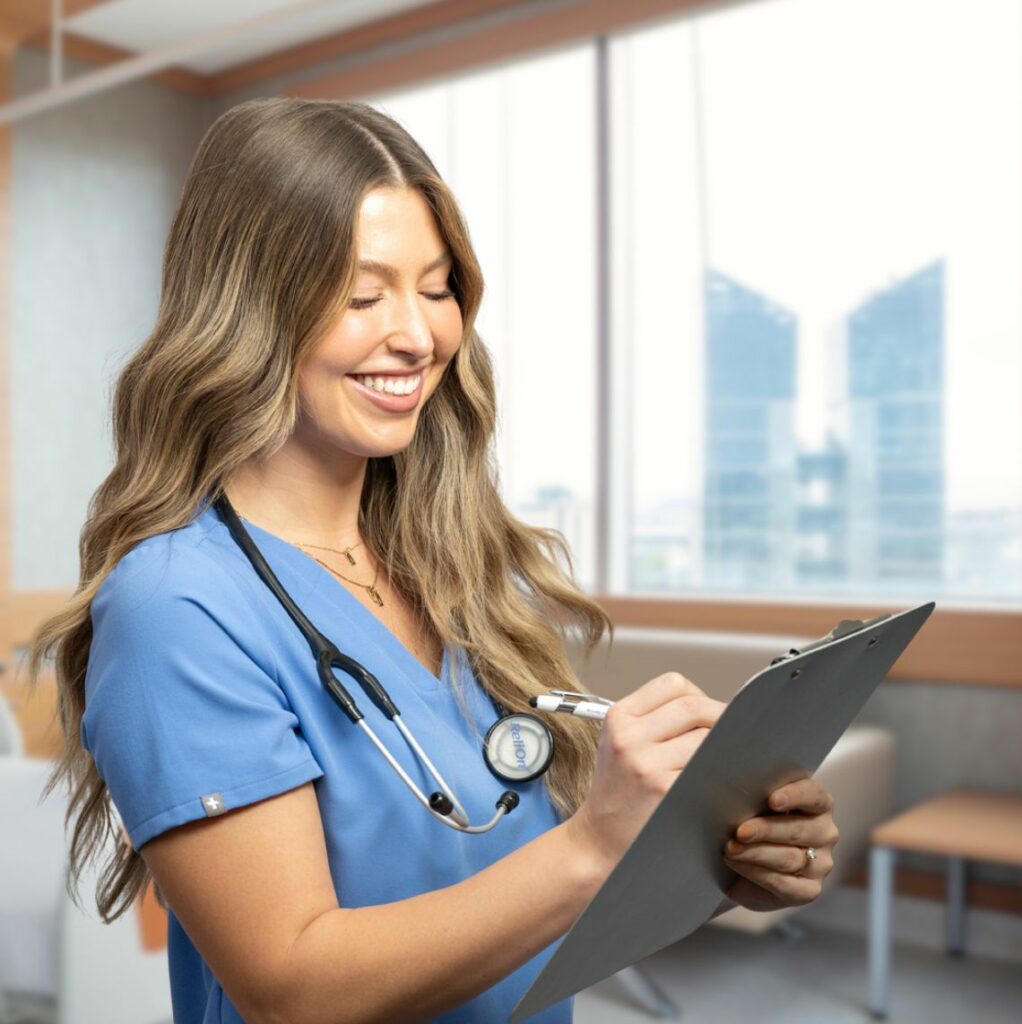 photo of young woman healthcare worker smiling and writing on a clipboard in a hospital room