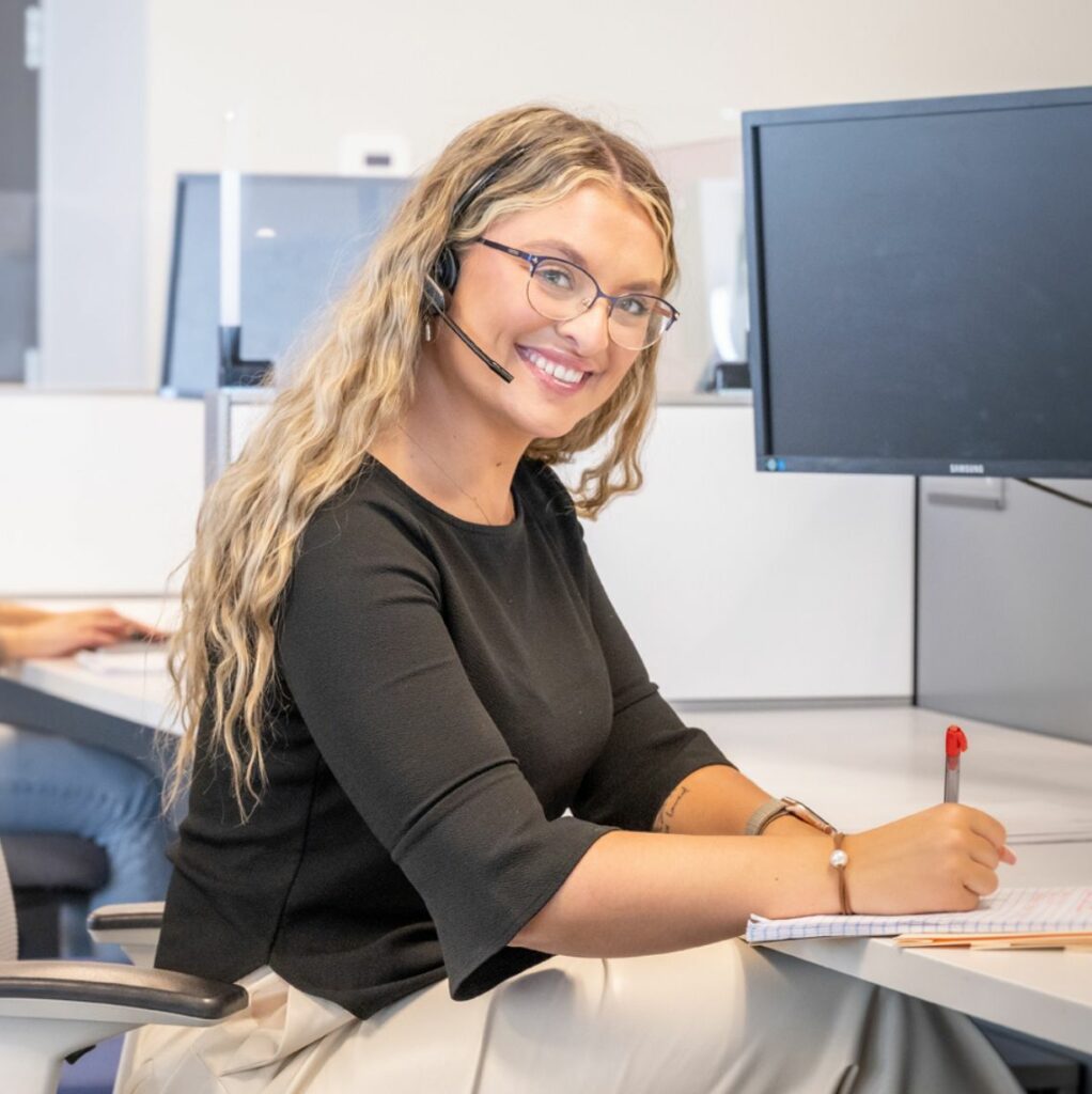 photo of recruiter smiling at camera and writing on a notepad