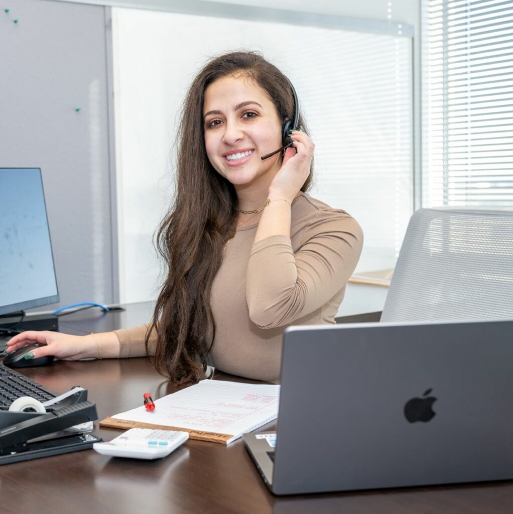 Photo of young woman recruiter with a headset on and smiling at the camera
