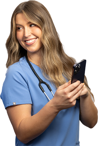 A medical professional in a blue scrub top with a stethoscope around their neck is focused on a smartphone