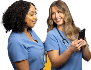 Two medical professionals in blue scrubs are engaged in a discussion. The person on the left has curly hair and is facing towards the right, while the person on the right, with straight hair, is holding a smartphone, possibly sharing information
